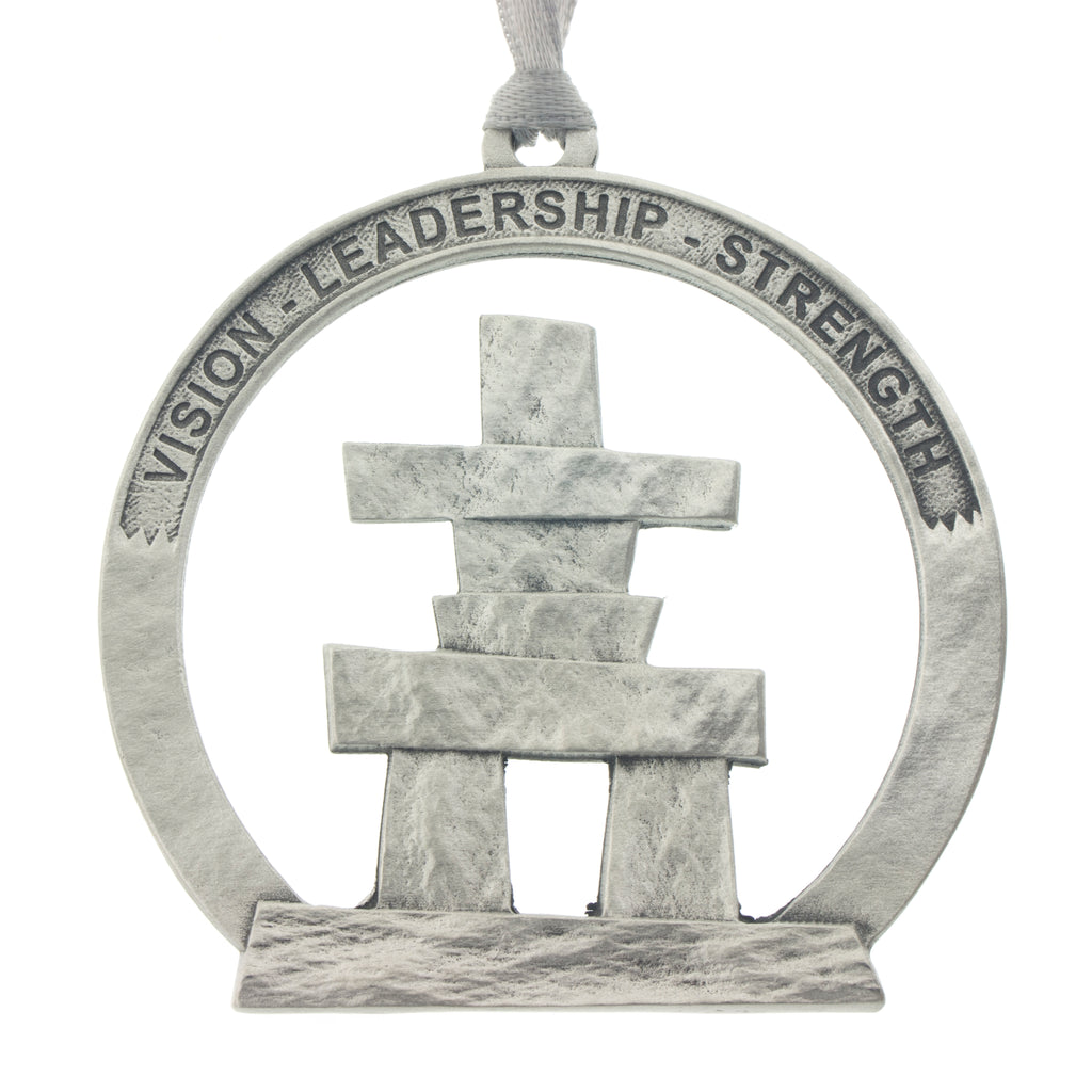 An Inukshuk on a circular cut out. Christmas Tree ornament. Made from Pewter. Silver ribbon. Made in Fredericton NB New Brunswick Canada