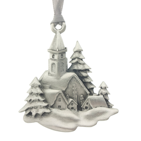A serene scene of a church and village snuggled under a blanket of snow. Christmas Tree ornament. Made from Pewter. Silver ribbon. Made in Fredericton NB New Brunswick Canada