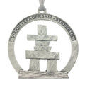 An Inukshuk on a circular cut out. Christmas Tree ornament. Made from Pewter. Silver ribbon. Made in Fredericton NB New Brunswick Canada