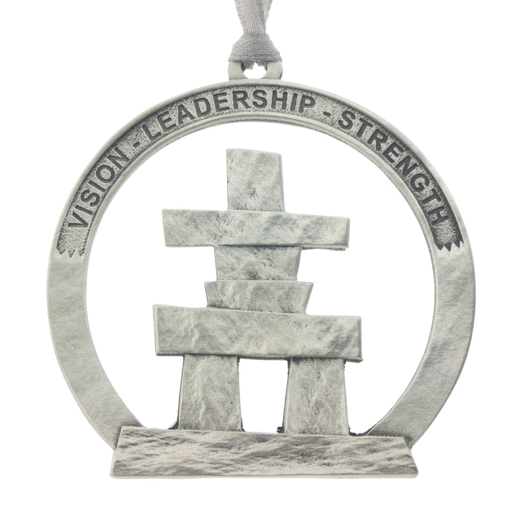 An Inukshuk on a circular cut out. Christmas Tree ornament. Made from Pewter. Silver ribbon. Made in Fredericton NB New Brunswick Canada